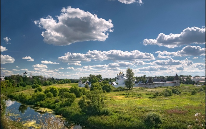 River and monastery complex under a cloudy sky