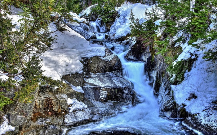 Winter waterfall flowing over rocks with snow and trees