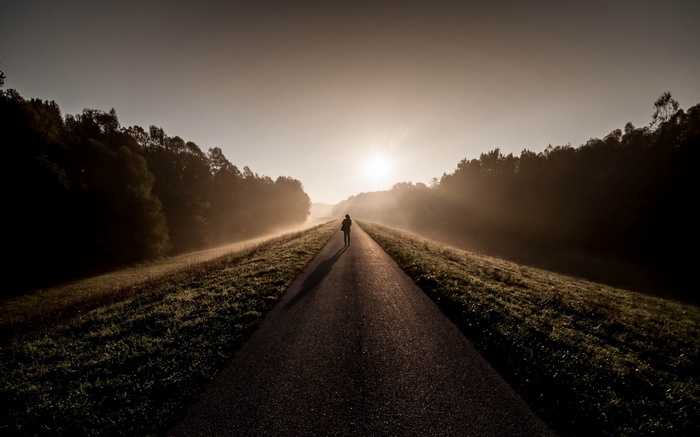 Person walking on a road at sunrise