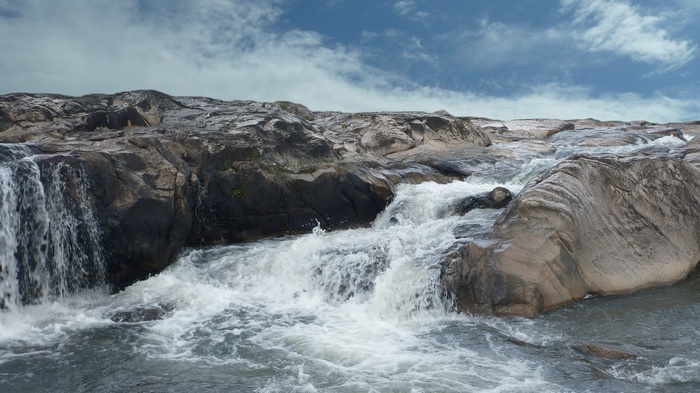 Rocky river with cascading water and blue sky