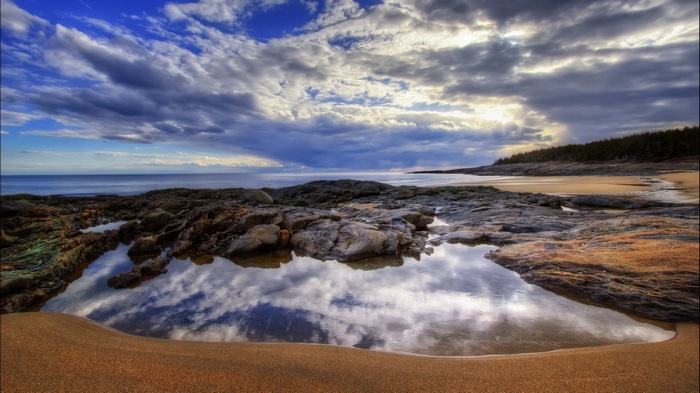 Rocky beach with tide pools reflecting clouds
