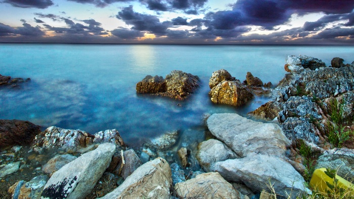 Rocky coastline with calm ocean and dramatic clouds