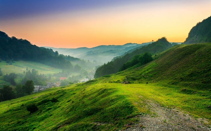 Misty valley with rolling green hills at sunrise
