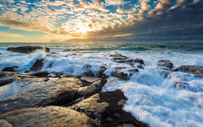 Waves crashing on rocky shore at sunset