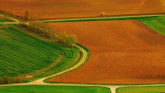 Tractor on a field with rolling hills and crops