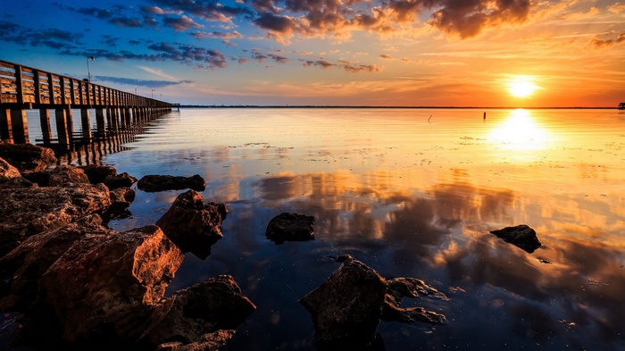 Sunset over a calm lake with a wooden pier