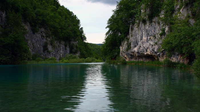 Turquoise lake between rocky cliffs and green forest