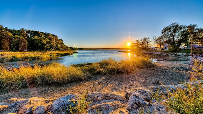 Sunset over a marshy river with trees and houses
