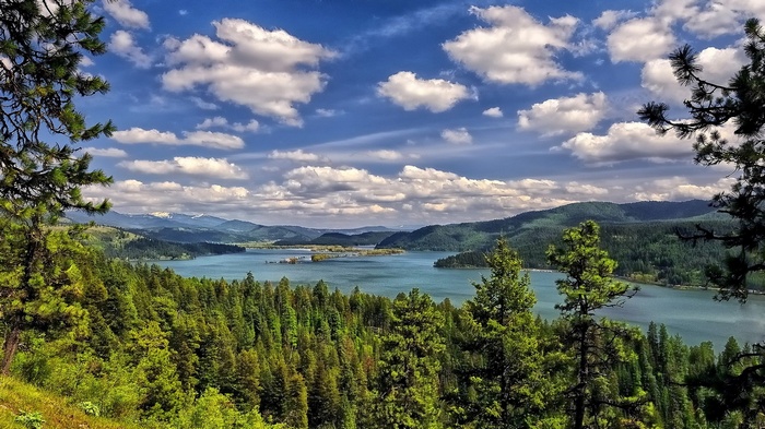 Lake surrounded by forested mountains under a cloudy sky