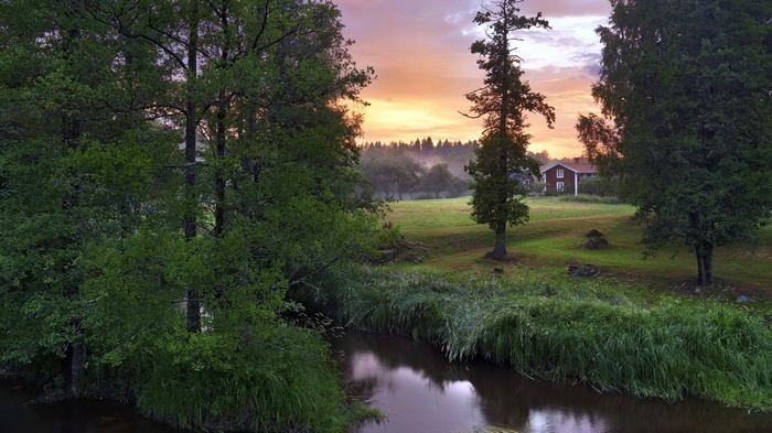 Red house by a river at sunset