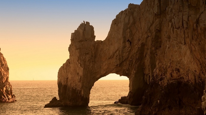 Arch rock formation over the ocean at sunset
