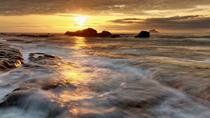 Sunset over rocky coastline with ocean waves