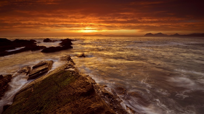Sunset over rocky coastline with ocean waves
