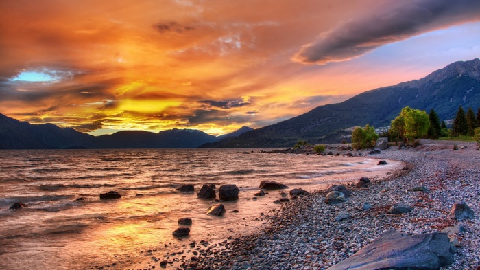 Sunset over a rocky lake shore with mountains