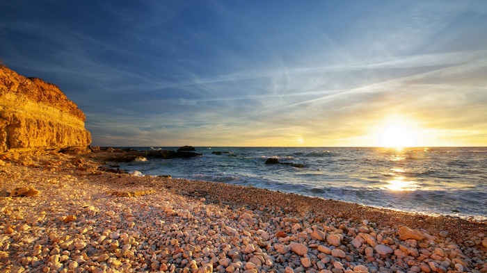 Rocky beach at sunset with ocean waves