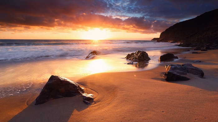 Sunset over a rocky beach with waves