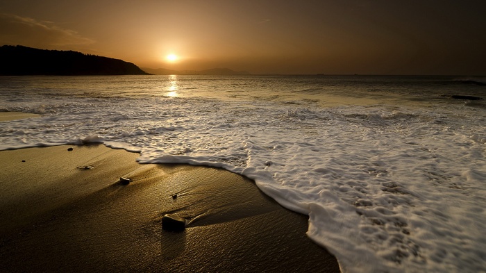 Sunset over the ocean with waves on the beach