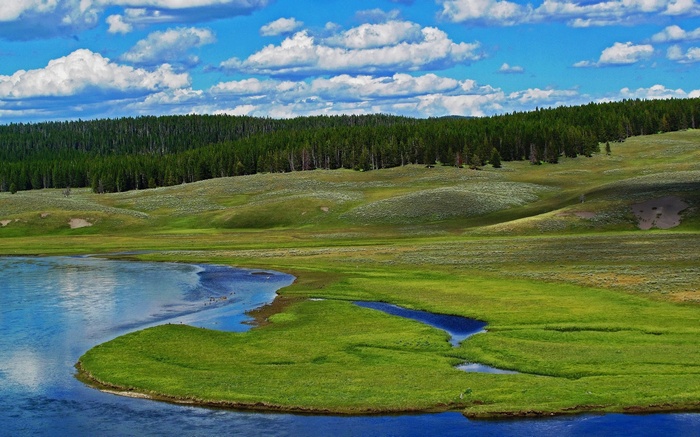 Green rolling hills and a blue lake under a cloudy sky