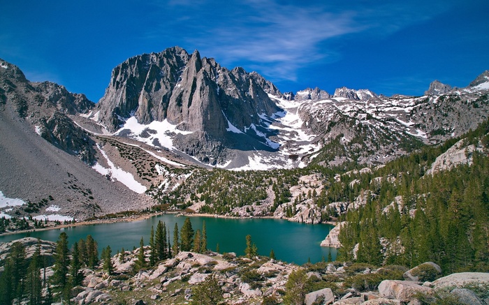 Turquoise lake surrounded by rocky mountains and pine trees