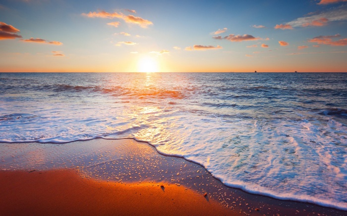 Sunset over the ocean with waves on the beach