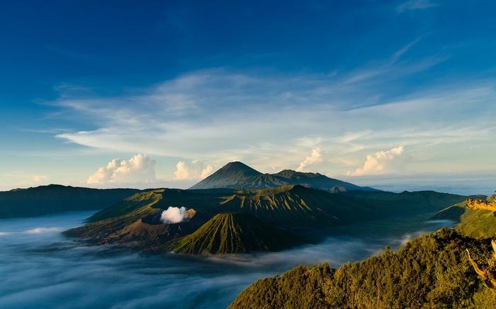 Volcanoes shrouded in mist under a blue sky