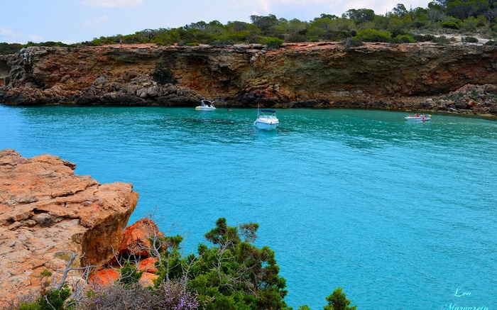 Boats in a turquoise cove with rocky cliffs