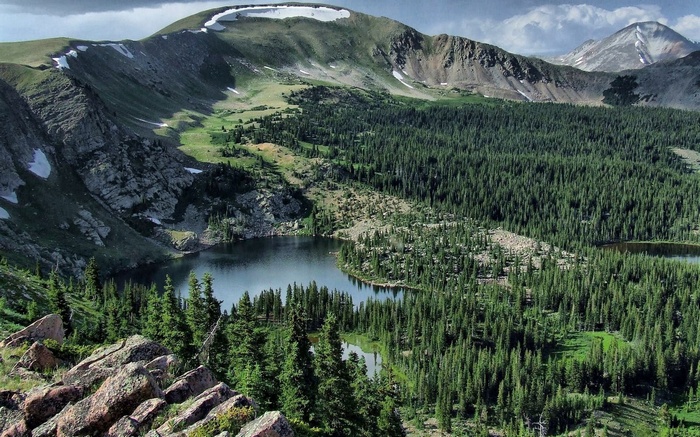 Mountain lake surrounded by pine forest and rocky slopes