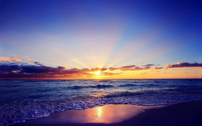 Sunset over the ocean with waves on the shore