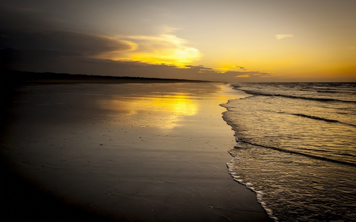 Sunset over a wet beach with ocean waves