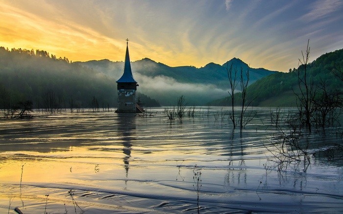 Flooded church tower in a lake at sunrise