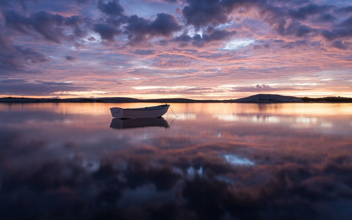 Boat on calm water at sunset