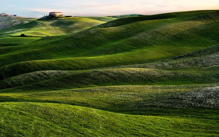 Rolling green hills with a house on a hilltop