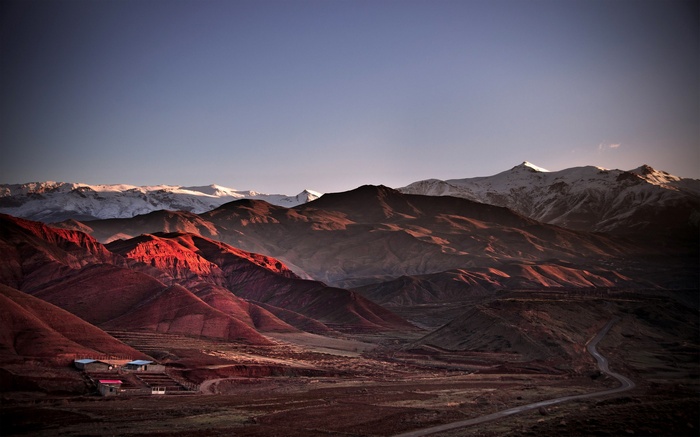 Mountain landscape with snow-capped peaks and red hills