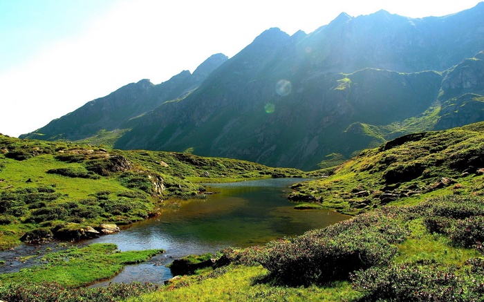 Mountain lake with green hills and rocky peaks