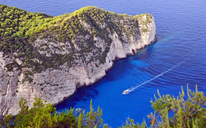 Boat sailing in blue water near a cliff