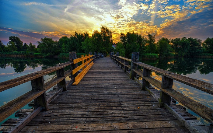 Wooden bridge over water at sunset