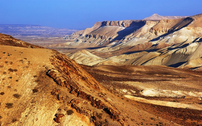 Desert landscape with layered rock formations under a blue sky