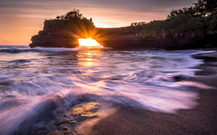 Sunset through rock arch at Tanah Lot, Bali