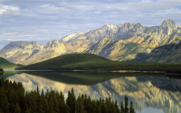 Mountain range reflected in a calm lake with pine trees