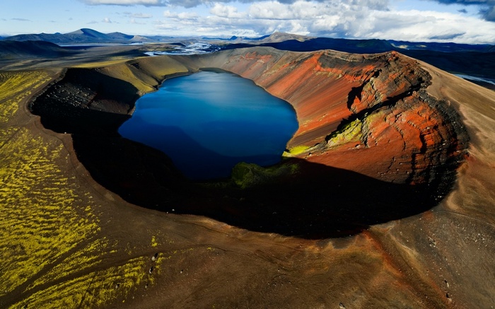 Aerial view of a volcanic crater lake with colorful slopes