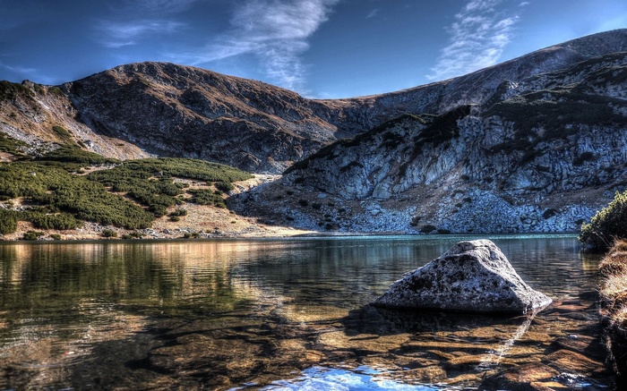 Mountain lake with rocky shore and slopes