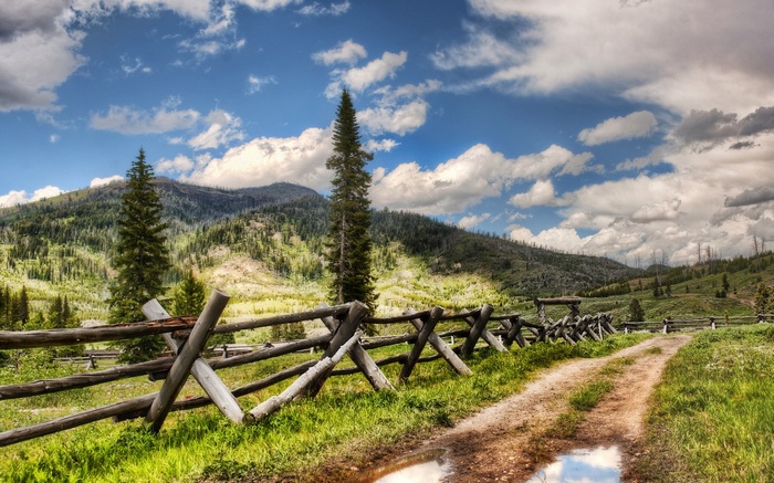 Dirt road with wooden fence and mountains
