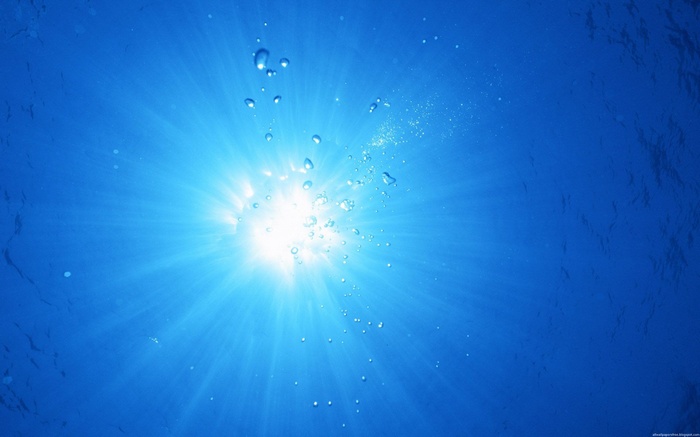 Sunlight shining through blue water with bubbles