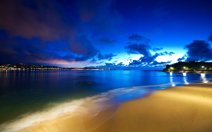 Beach at twilight with city lights across the water