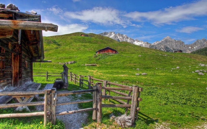 Wooden cabin and fence in a green mountain landscape