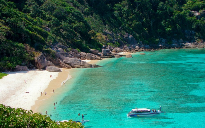 Tropical beach with clear turquoise water and a speed boat