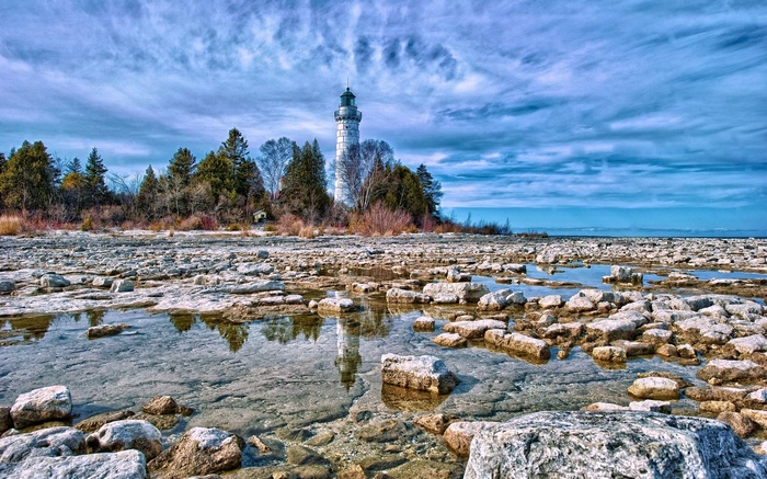 Lighthouse on a rocky shore with reflections