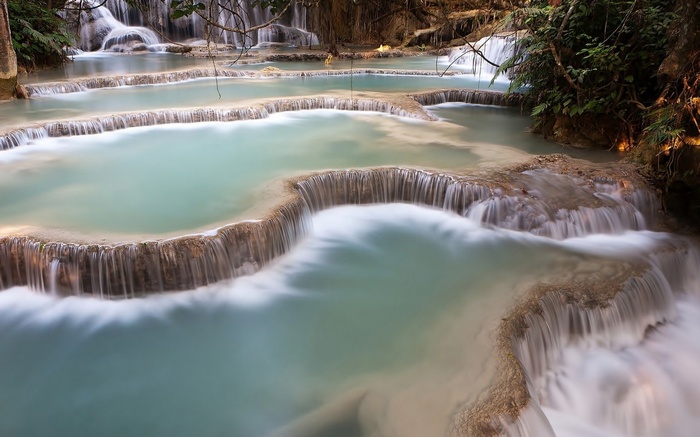 Tiered turquoise waterfalls cascading over travertine terraces