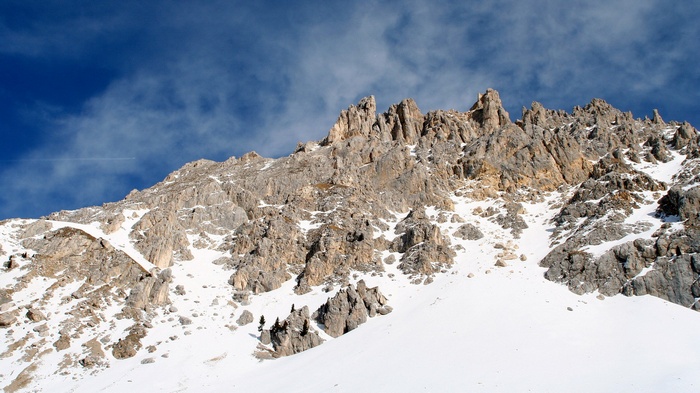 Snow-covered rocky mountain range under a blue sky