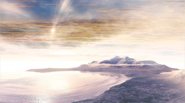 Sunlight over a snowy mountain range and ocean